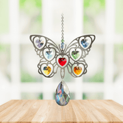 Handmade Butterfly Rainbow crystal suncatcher displayed on a wooden table in front of a bright window

