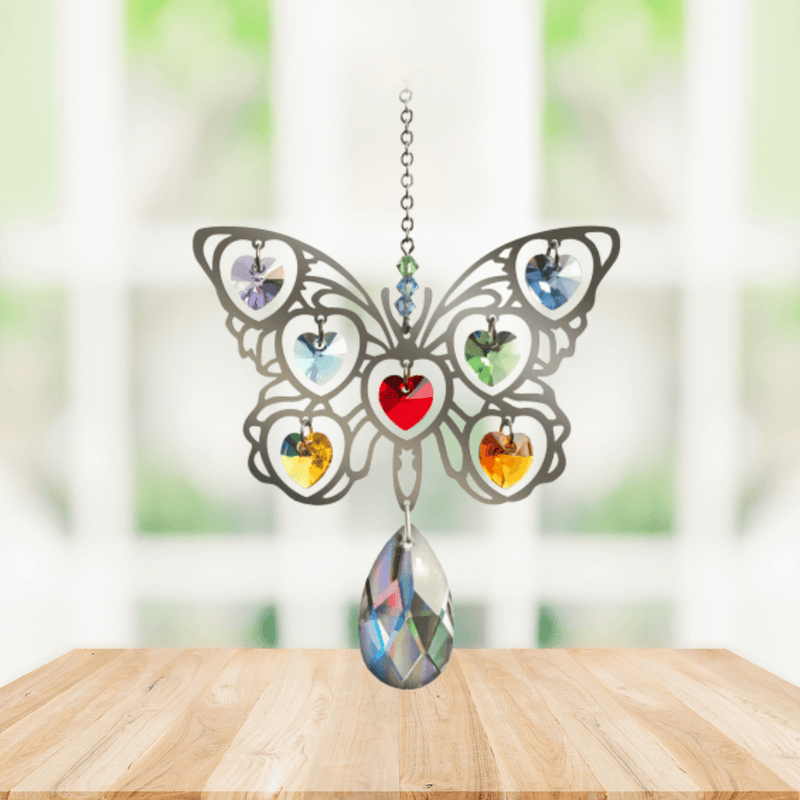 Handmade Butterfly Rainbow crystal suncatcher displayed on a wooden table in front of a bright window

