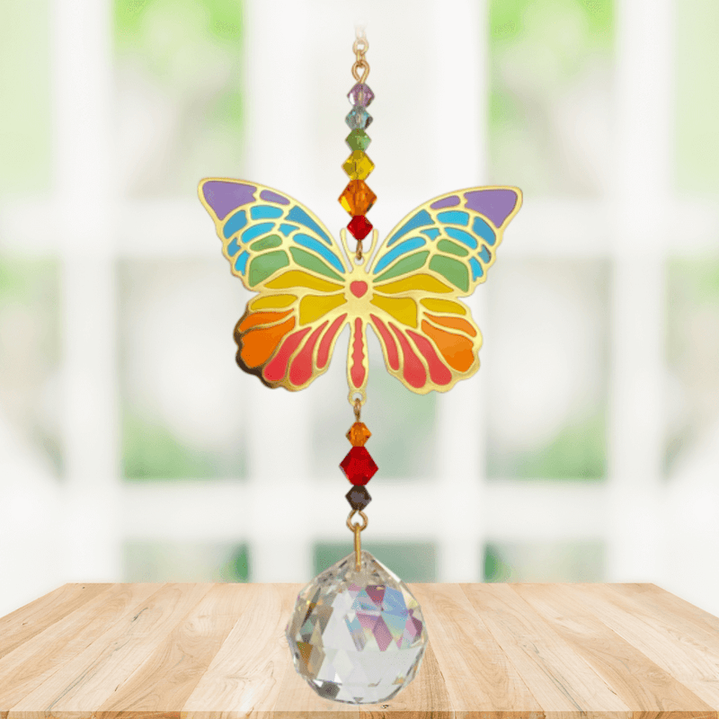 Butterfly Rainbow Crystal Suncatcher hanging in sunny window; rainbow enamel wings, chakra-style beads and sparkling crystal ball.

