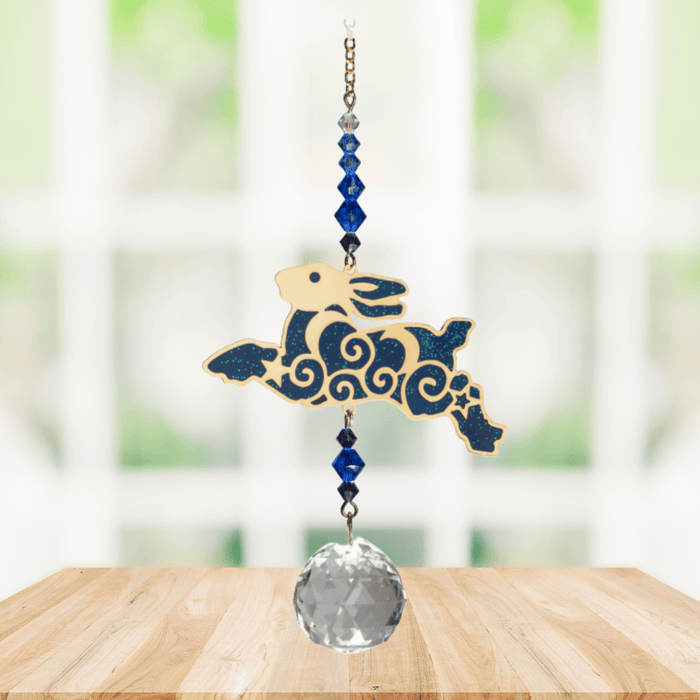 Wild Things Crystal Dreams Running Hare suncatcher hanging by a window with deep blue hare and crystal drop