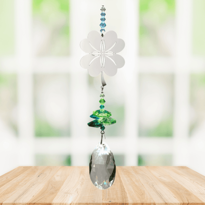 Wild Things Crystal Fantasy Four Leaf Clover suncatcher hanging by a window with green and blue crystals
