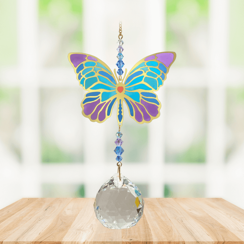 Wild Things Crystal Wonders iris butterfly crystal suncatcher hanging in a bright window, mirror-gold motif with teal and purple detail and 30mm crystal ball.