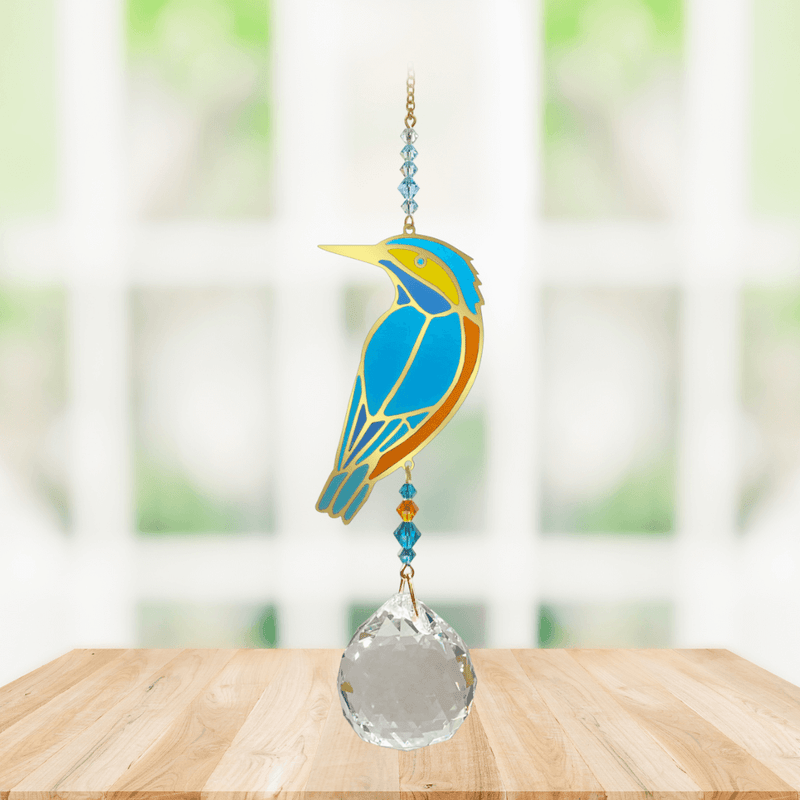 Wild Things Crystal Wonders kingfisher crystal suncatcher hanging in a bright window, mirror-gold bird motif in blue and gold with 30mm crystal ball pendant.