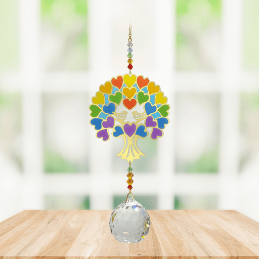 Wild Things Crystal Wonders Tree of Life rainbow crystal suncatcher hanging in a bright window, mirror-gold motif with rainbow hearts and 30mm crystal ball pendant.