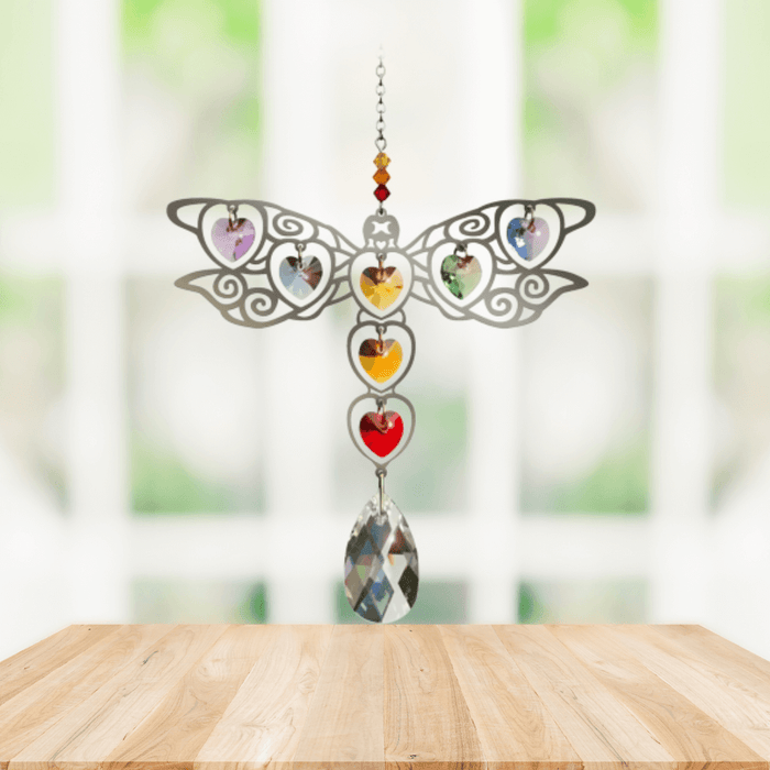 Handmade Dragonfly Rainbow crystal suncatcher displayed on a wooden table before a bright window


