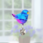 Handmade blue-and-violet Evening Song crystal suncatcher shining before soft blooms

