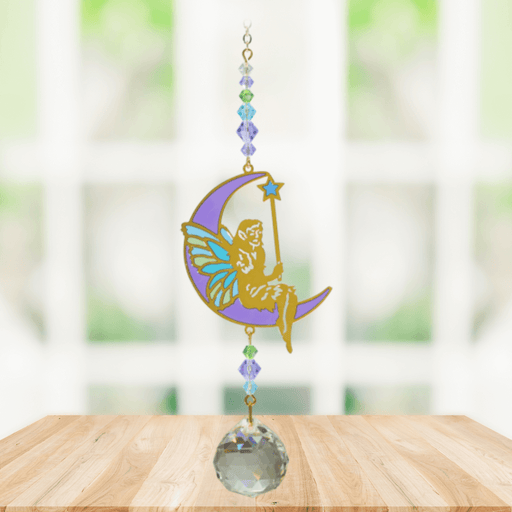 Fairy Aurora Crystal Suncatcher hanging in a bright window; moon-perched fairy, aqua-lilac-green bead cascade and sparkling crystal ball ready to cast rainbows.
