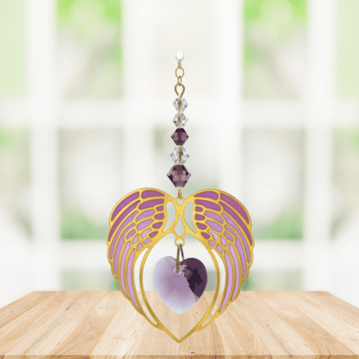 Gold angel wing heart suncatcher with amethyst purple crystal heart hanging in a bright window
