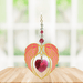 Gold angel wing heart suncatcher with ruby red crystal heart hanging in a bright window
