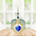 Gold angel wing heart suncatcher with sapphire blue crystal heart hanging in a bright window
