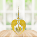 Gold angel wing heart suncatcher with topaz crystal heart hanging in a bright window
