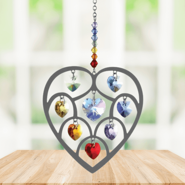 Handmade Heart of Hearts Chakra crystal suncatcher displayed on a wooden table in front of a bright window

