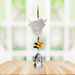 Wild Things Highland Cow Autumn Gold crystal suncatcher hanging in a window with amber beads, butterfly crystals and clear teardrop prism
