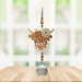 Wild Things Highland Cow Brown crystal suncatcher hanging in front of a window with amber beads and clear crystal prism