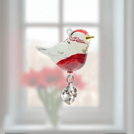 Handmade red-breasted Robin crystal suncatcher glowing in front of blurred red blooms

