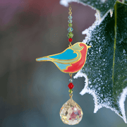 Robin Crystal Suncatcher beside frosted holly; blue-red robin, festive bead cascade and 20 mm prism scattering rainbows.

