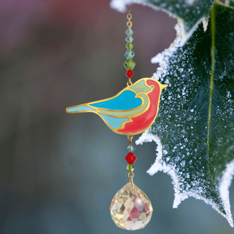 Robin Crystal Suncatcher beside frosted holly; blue-red robin, festive bead cascade and 20 mm prism scattering rainbows.

