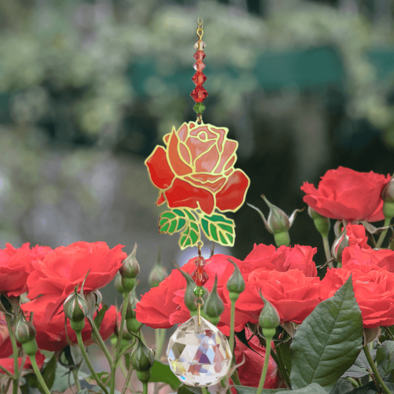 Rose Crystal Suncatcher among garden roses – enamel flower, jewel-tone bead cascade and 20 mm prism scattering rainbow light.

