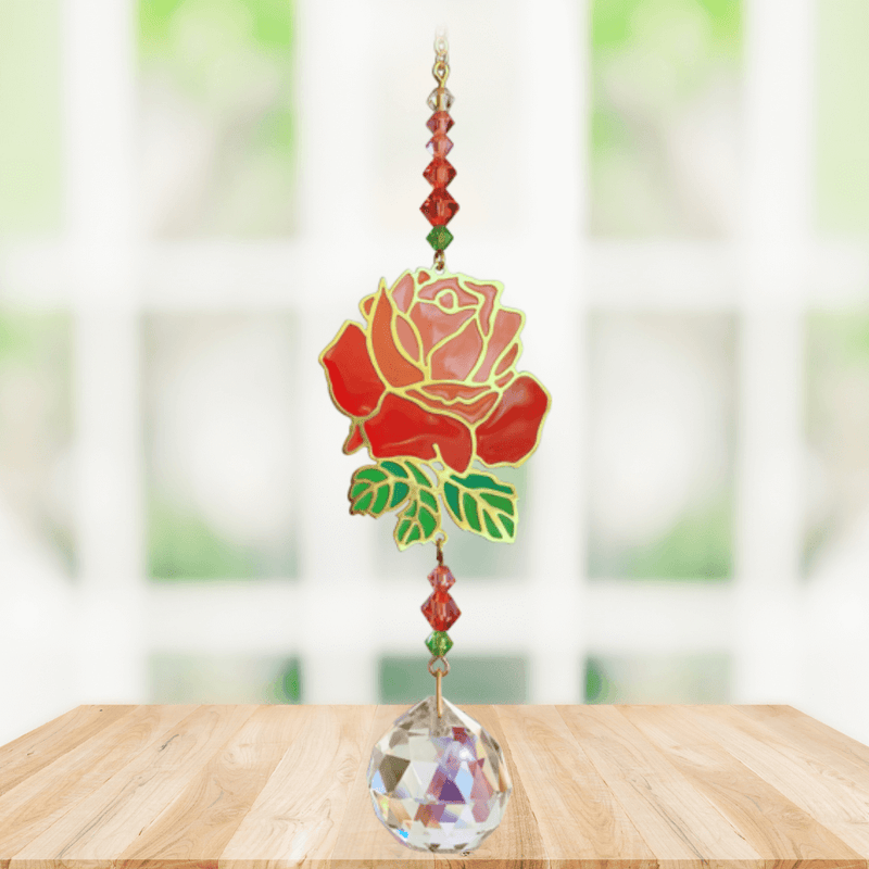 Rose Crystal Suncatcher hanging in sunny window; vivid red rose motif, faceted red-green beads and sparkling crystal ball.
