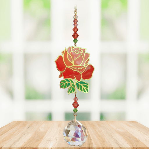 Rose Crystal Suncatcher hanging in sunny window; vivid red rose motif, faceted red-green beads and sparkling crystal ball.
