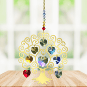 Handmade gold Tree of Life Chakra crystal suncatcher displayed on a wooden table before a bright window

