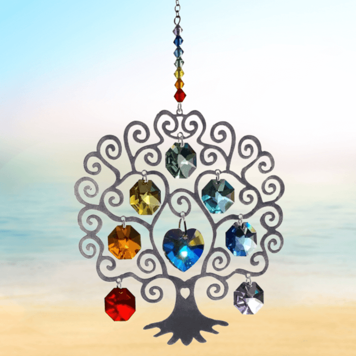 Large Tree of Life Chakra crystal suncatcher sparkling against a calm seaside horizon

