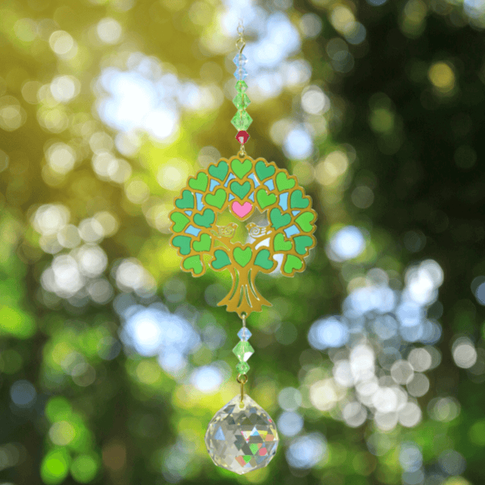 Tree of Life Green Crystal Suncatcher catching woodland light – vibrant heart-leaf canopy, emerald beads and 20 mm prism scattering rainbow shards.

