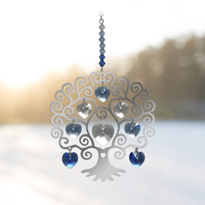 Tree of Life winter crystal suncatcher catching low sunlight against a snowy landscape

