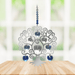 Polished metal Tree of Life winter suncatcher with blue crystal heart drops displayed on a wooden table

