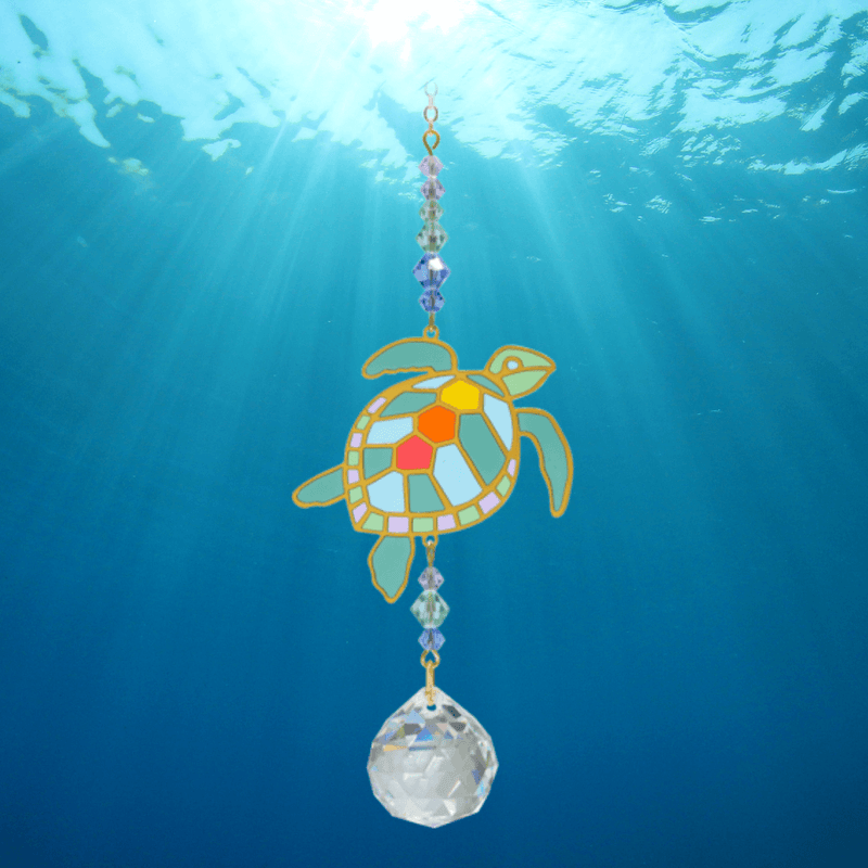 Turtle Marine Crystal Suncatcher floating in sun-dappled water – colourful shell motif, ocean-tone beads and 20 mm prism scattering light.

