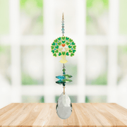 Tree of Life green Window Jewels crystal suncatcher hanging in a bright window, mirror-gold motif with green crystals and clear drop.