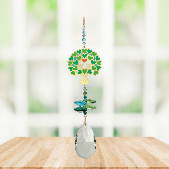 Tree of Life green Window Jewels crystal suncatcher hanging in a bright window, mirror-gold motif with green crystals and clear drop.