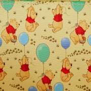 Close-up of interior lining with Winnie the Pooh, balloons, and bees on yellow fabric