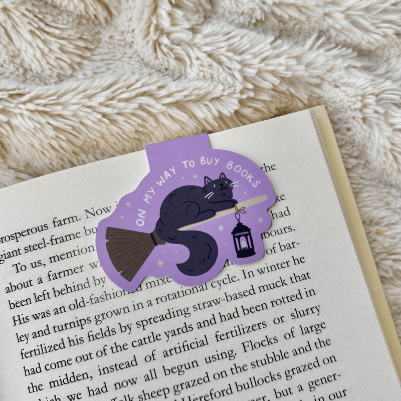 Witch Cat magnetic bookmark clipped over the page of an open book
