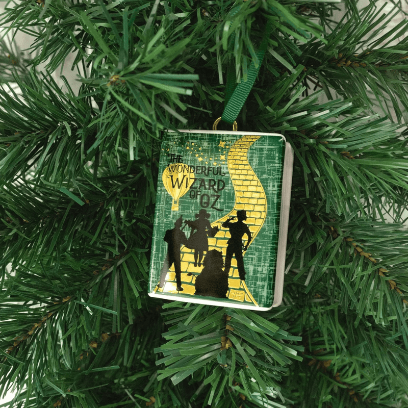 Wizard of Oz ceramic book ornament hanging on a Christmas tree, featuring the golden Yellow Brick Road
