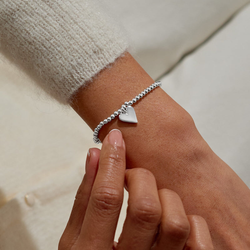 “Lifestyle shot of woman wearing the ‘Merry Christmas’ heart bracelet”
