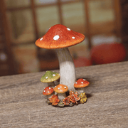 Lifestyle photo of a small autumn toadstool ornament on a wooden surface with a blurred rustic backdrop.