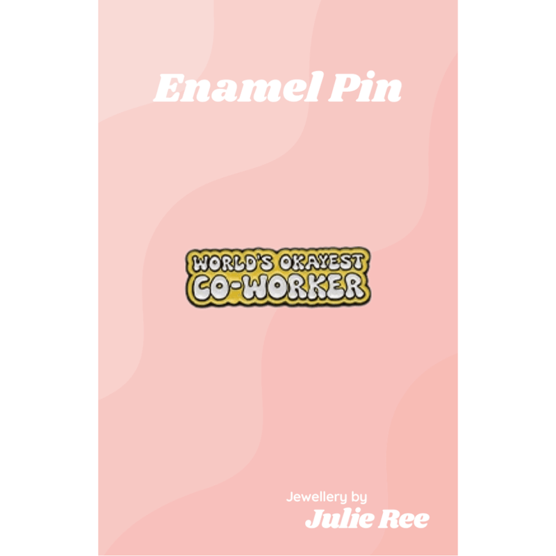 Yellow enamel pin with the phrase World’s Okayest Co-Worker in bold lettering, displayed on a pink backing card.