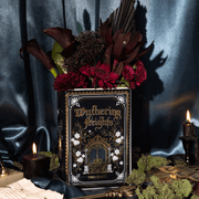 Wuthering Heights ceramic book vase styled with dark red flowers, candles and moody blue fabric backdrop