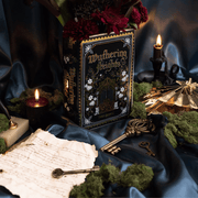 Wuthering Heights ceramic book vase styled with keys, candles and vintage paper props on a dark blue backdrop