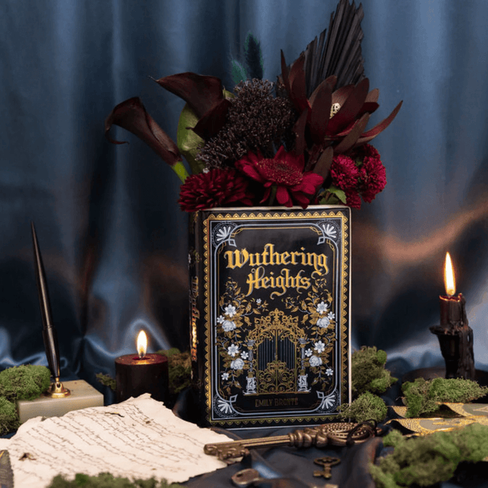 Wide styled scene featuring the Wuthering Heights ceramic book vase with flowers, candles and vintage stationery