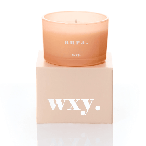 Peach frosted glass WXY Aura candle sitting on a matching WXY box on a white background.