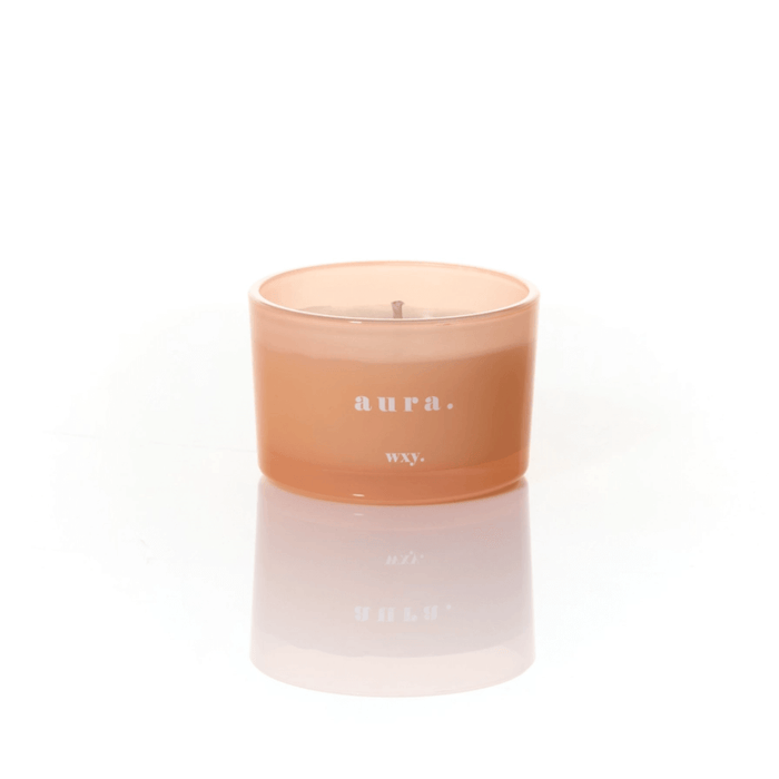 Peach frosted glass WXY Aura candle with white wax and a centred wick on a white background.