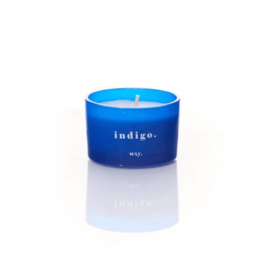 Blue glass WXY indigo candle with white wax and a centred wick on a white background.