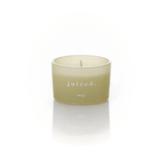 Pale green frosted glass WXY juiced candle with white wax and a centred wick on a white background.