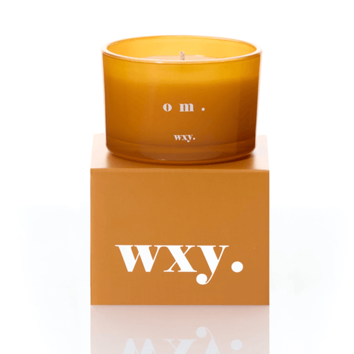 Amber glass WXY om candle displayed on a matching WXY box on a white background.