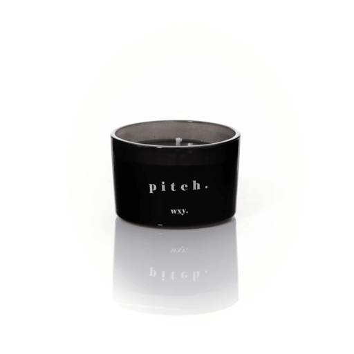 Black glass WXY pitch candle with white wax and a centred wick on a white background.