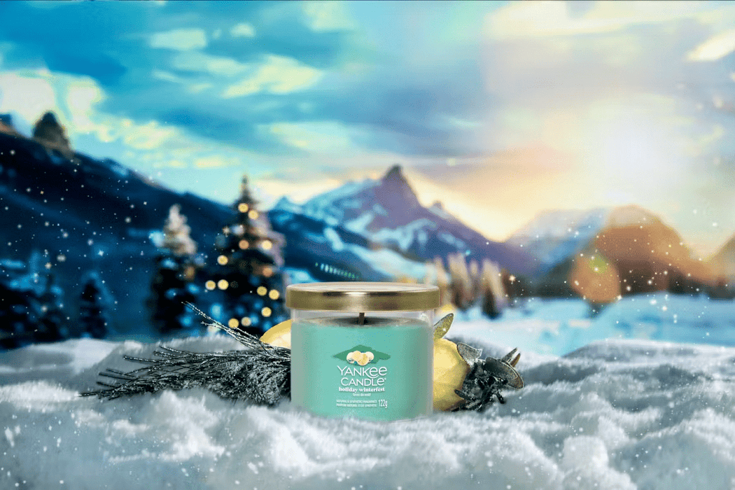 Holiday Winterfest candle in snowy alpine scene with lemon and pine sprig at sunrise