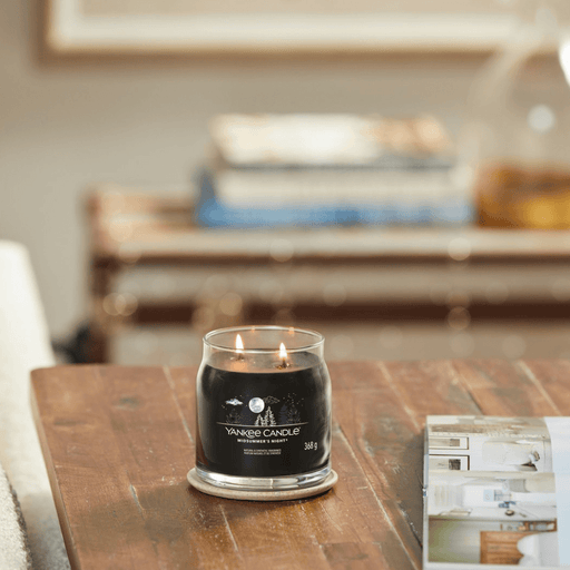 Yankee Candle Midsummer's Night medium Signature jar scented candle lit on a wooden table, dark wax lifestyle image
