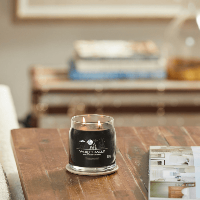Yankee Candle Midsummer's Night medium Signature jar scented candle lit on a wooden table, dark wax lifestyle image